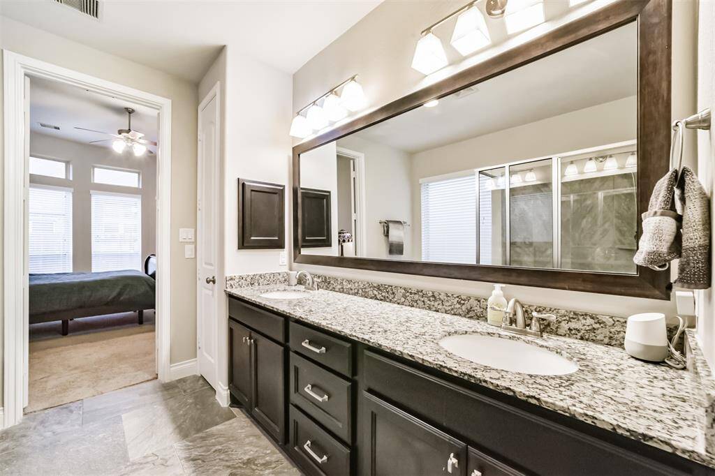 Primary en-suite bathroom exudes luxury, featuring designer touches. Framed mirror, dual sinks and ample counter space.