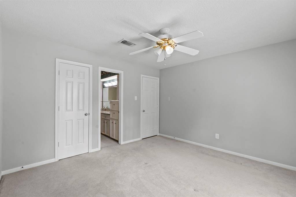 Great closet and entrance to a shared Jack and Jill bath in this secondary bedroom. Neutral paint, white trim, ceiling fan.