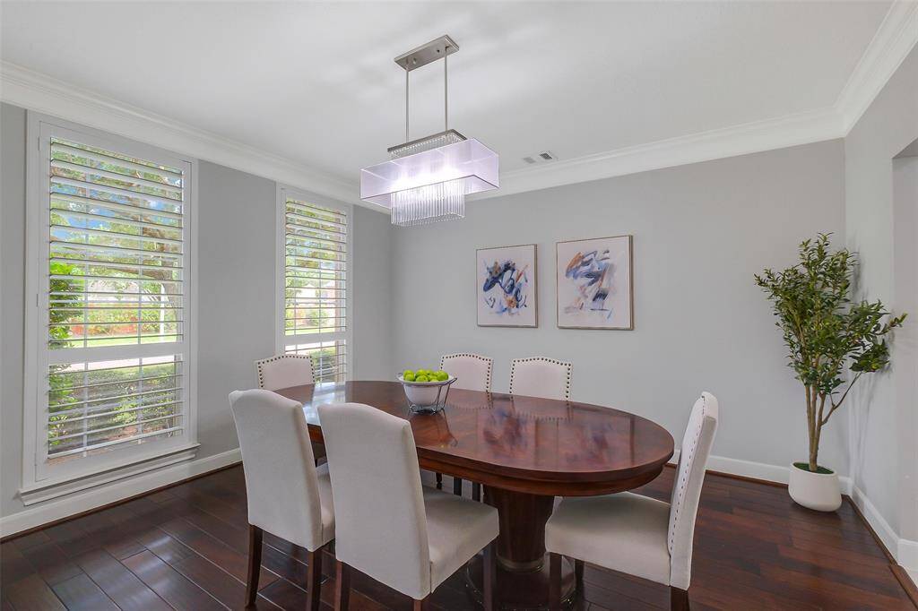 The formal dining room is an inviting space designed for memorable gatherings, with generous proportions, timeless crown molding, and soft natural light filtering through expansive windows. Anchored by a designer chandelier, the room offers a graceful setting for entertaining, seamlessly blending classic elegance with everyday comfort.