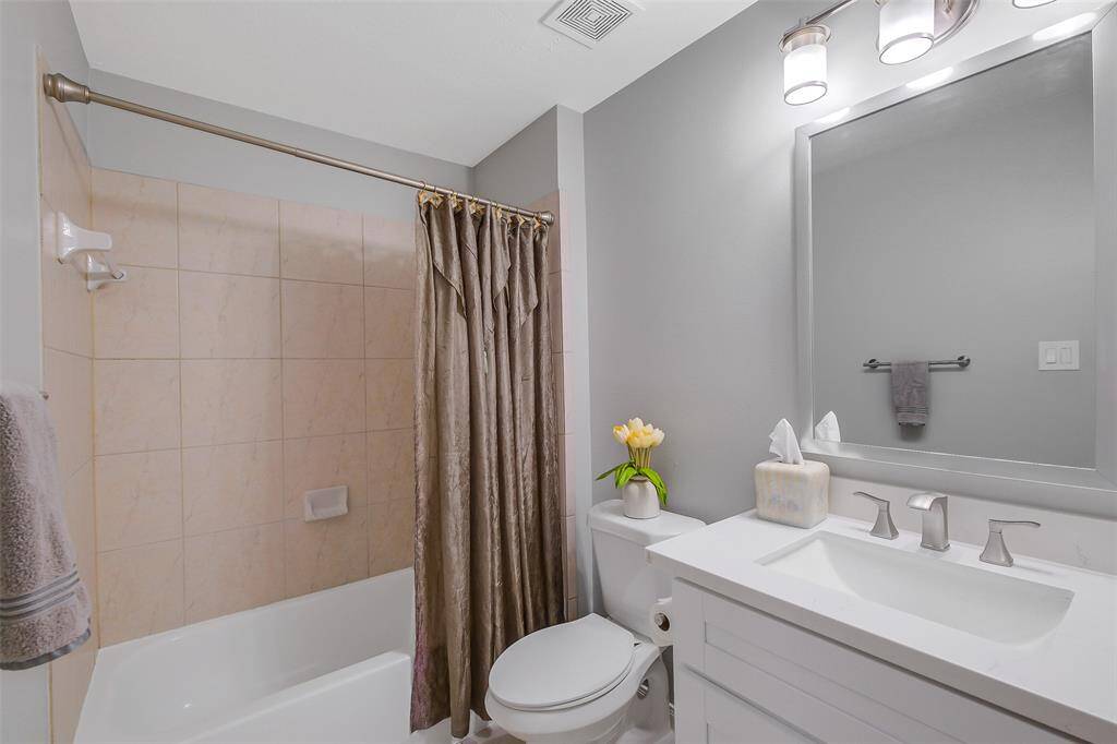 This charming secondary bedroom is a peaceful retreat, featuring soft, neutral tones and ample natural light. A cozy bed with plush linens is complemented by a spacious closet and elegant furnishings, creating a comfortable, inviting space.