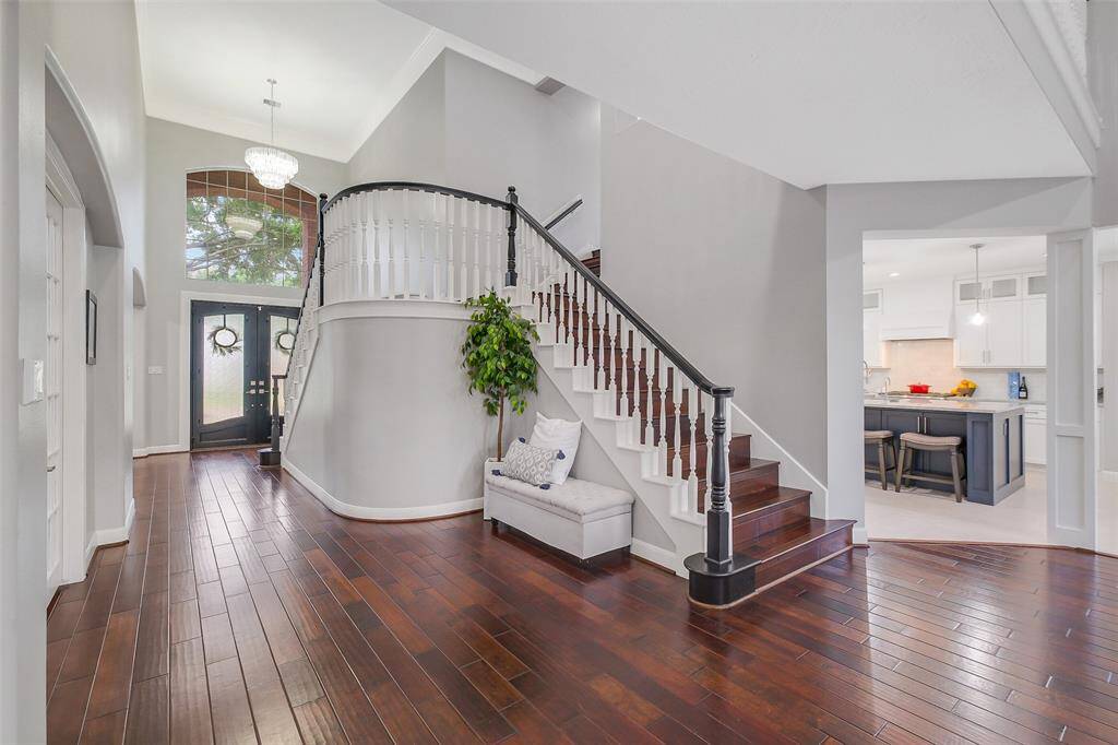 An architectural focal point, the grand staircase boasts custom woodwork, wrought iron balusters, and a sweeping curve that elevates the home's timeless charm.