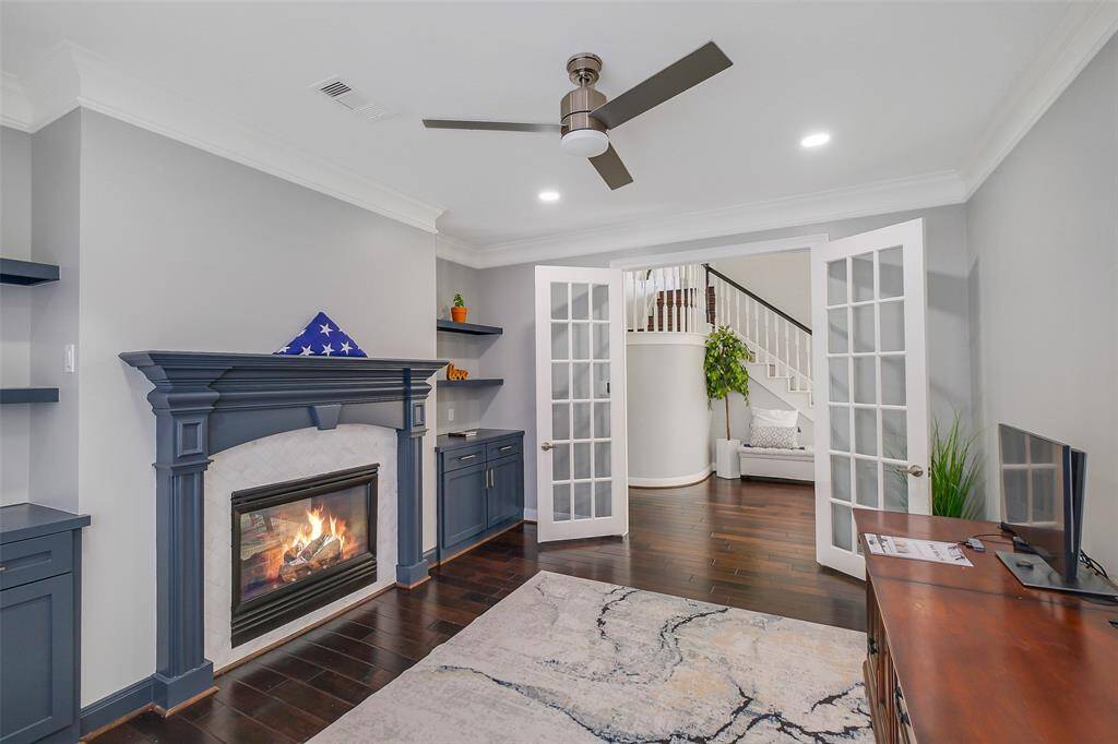 This refined study exudes warmth and sophistication, featuring a stately fireplace as its centerpiece and framed by rich wood detailing. Natural light pours in through classic French doors, offering a seamless transition to the outdoor space while lending an airy charm to this private retreat—ideal for work, reading, or quiet reflection.