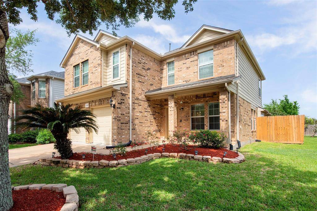 A charming two-story brick home with a well-maintained front lawn and landscaped garden. It features a double garage and a cozy porch, offering a welcoming curb appeal in a serene setting.