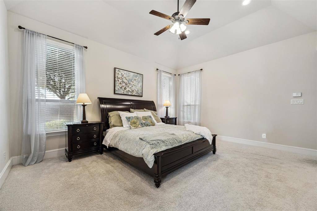 Spacious primary bedroom with abundant natural light, plush carpeting, and elegant finishes.