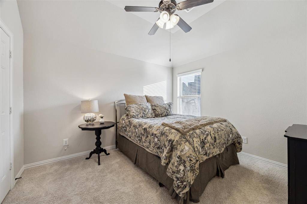 Comfortable bedroom with plush carpeting, ample closet space, and a ceiling fan for added comfort.
