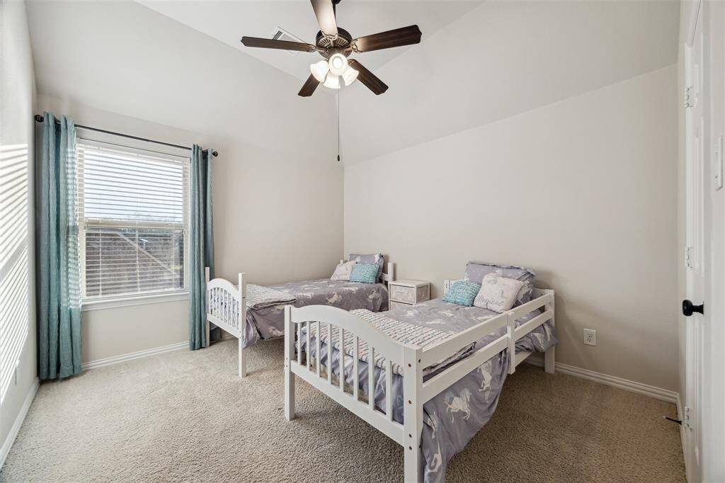 Cozy bedroom with natural light, plush carpeting, and a ceiling fan for comfort. Perfect for relaxation.
