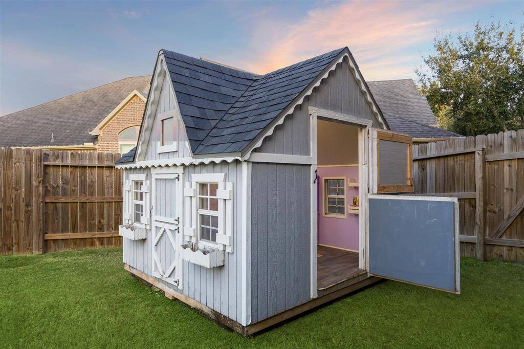 Charming custom playhouse in a spacious backyard, perfect for family fun and outdoor adventures.