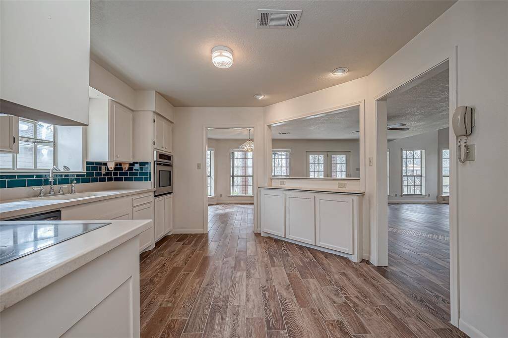 From this angle, the kitchen’s layout shines—partially enclosed by textured white walls, yet still open to the rest of the home. The cutout and two open doorways keep the space connected while maintaining a sense of structure. This design allows for easy interaction with guests or loved ones while cooking.