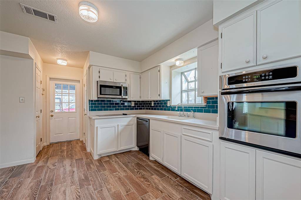 This kitchen’s white cabinetry and walls create a crisp, clean look, accented by a striking green tiled backsplash.