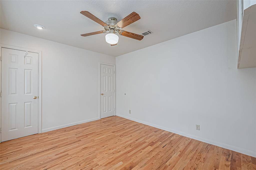 Spacious and well-lit, this bedroom offers a comfortable retreat with a ceiling fan overhead for added comfort. The built-in overhead shelf provides extra storage while maintaining a sleek, uncluttered look.