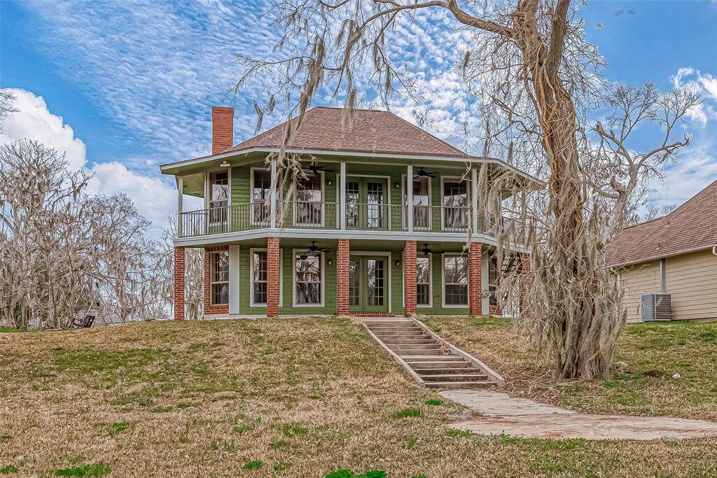 The home’s vibrant facade immediately draws attention, with its deep earth-toned brickwork and lush green exterior blending beautifully with the landscape. The expansive driveway leads to a two-car garage, providing ample space for parking and storage.