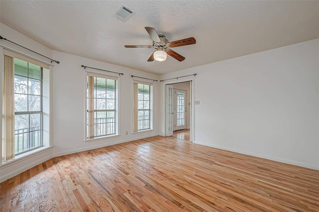 Expansive and full of natural light, this primary bedroom features oversized windows that bring in breathtaking outdoor views. The wood flooring adds warmth, while the ceiling fan ensures year-round comfort.