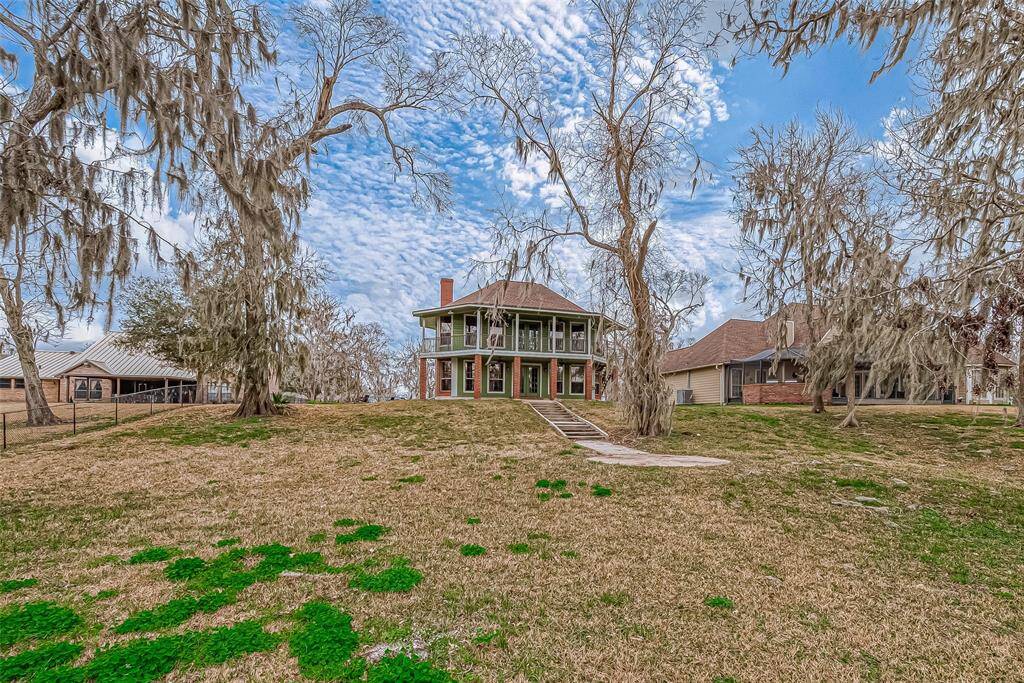 From a distance, the home’s architectural details come to life—large windows, brick pillars, and the expansive balcony and patio create a striking presence against the natural backdrop.