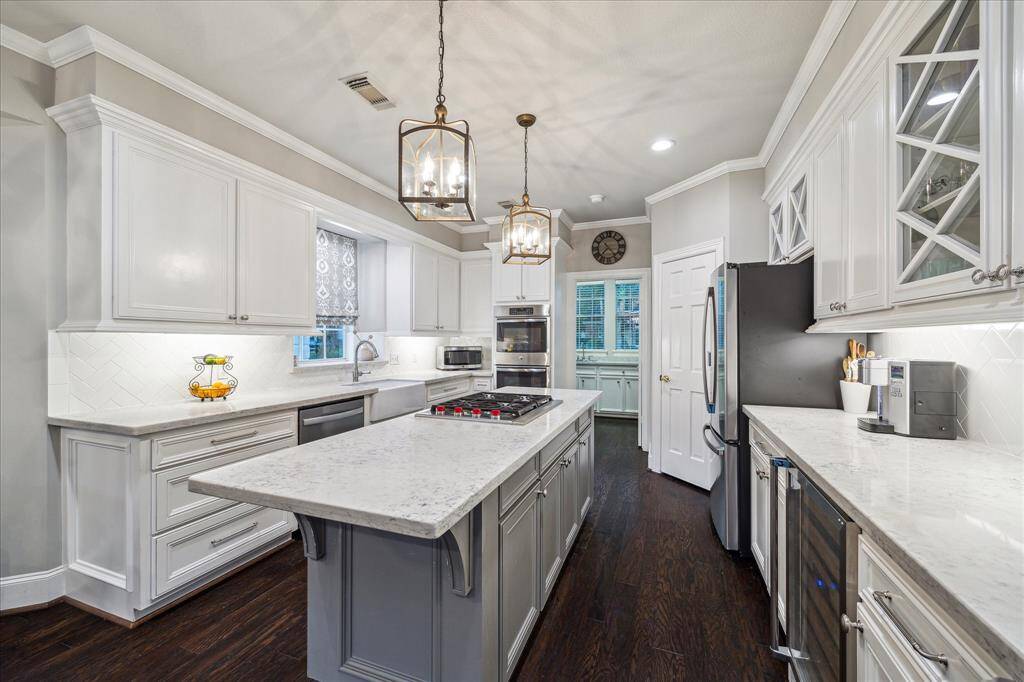 Sleek granite countertops with crisp white cabinetry, island with Wolf cooktop, double ovens and wine refrigerator!