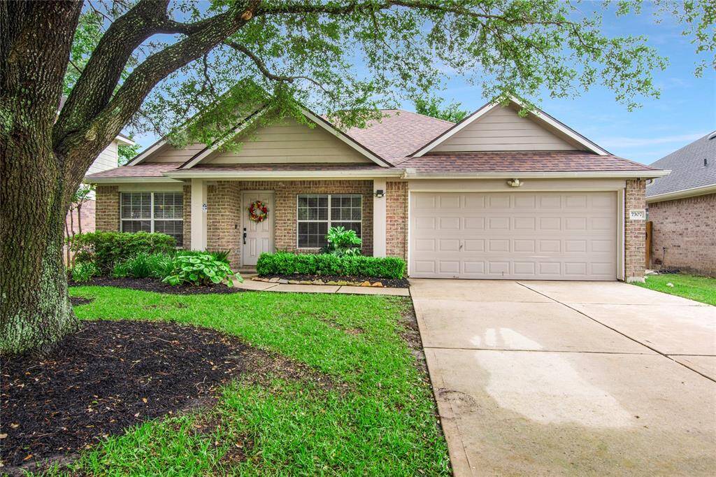 Charming single-story home with a welcoming front porch, lush landscaping, and a two-car garage.