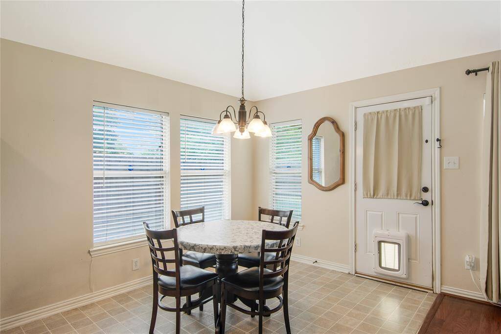 The breakfast area is brightened by natural light streaming through two large windows, complemented by a modern hanging light fixture. A door provides easy access to the outdoors, blending indoor and outdoor living seamlessly.