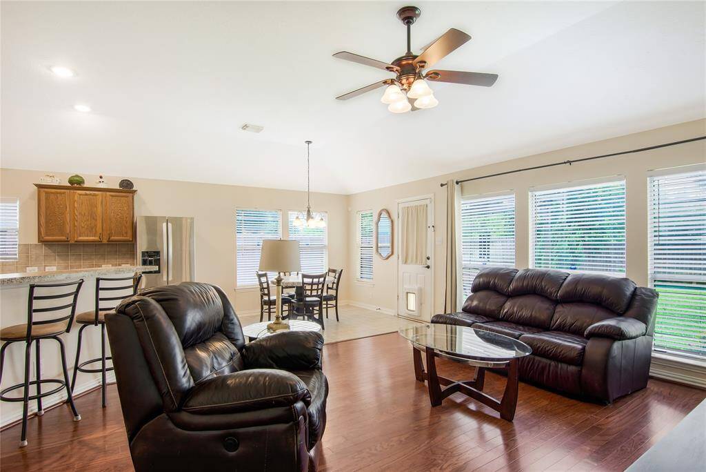 This inviting living space boasts an open-concept design with hardwood floors, ample natural light, and a cozy atmosphere. The kitchen features a breakfast bar, modern appliances, and warm wooden cabinets, while the adjacent breakfast area is brightened by large windows, creating a seamless flow throughout the space.