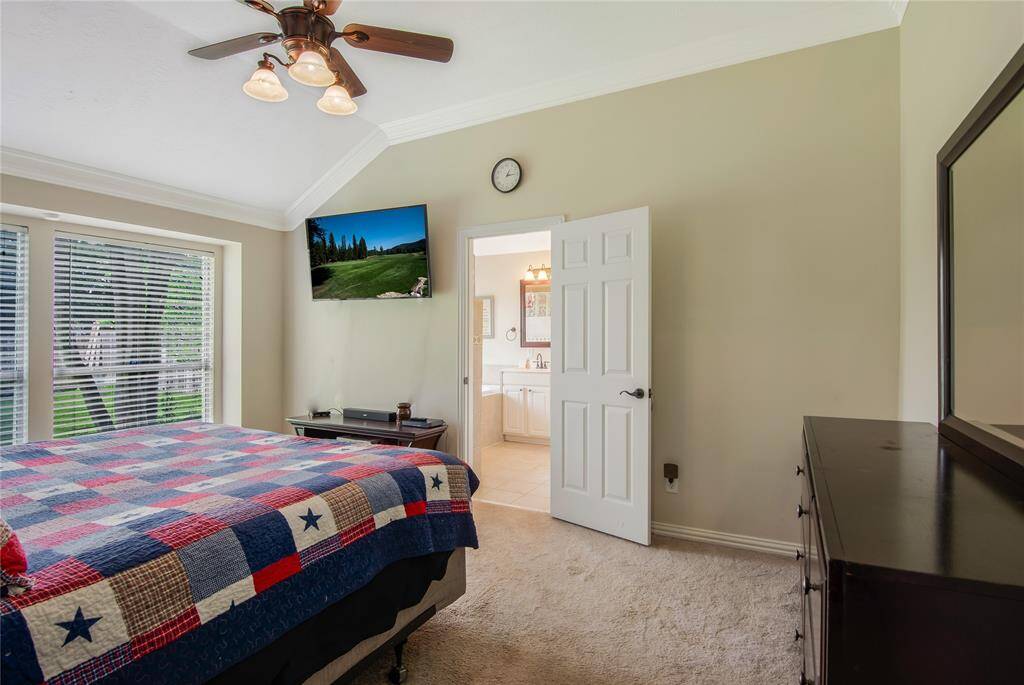 The primary bedroom boasts a vaulted ceiling with a ceiling fan, large windows that fill the room with natural light, and an ensuite bathroom for added convenience and privacy.
