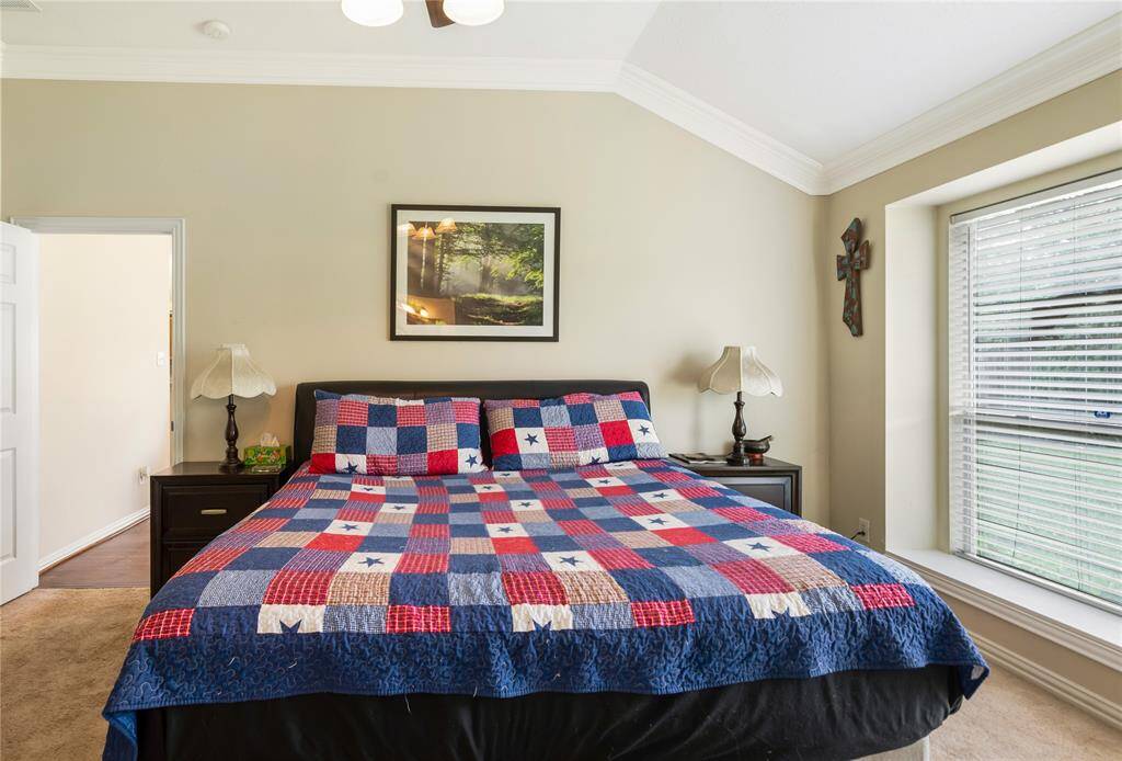 This cozy bedroom features a vaulted ceiling and a large window that lets in plenty of natural light. The neutral walls enhance the serene and tranquil atmosphere of the space.