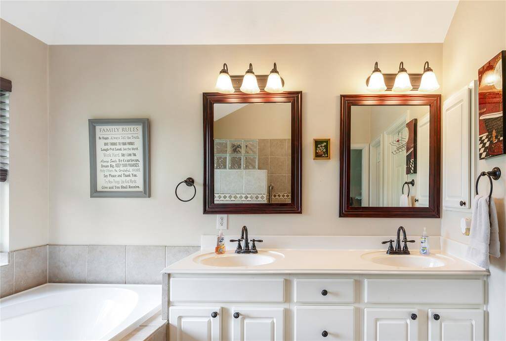 This bathroom offers a bright, airy feel with dual sinks, framed mirrors, and stylish lighting add to the serene and inviting atmosphere.