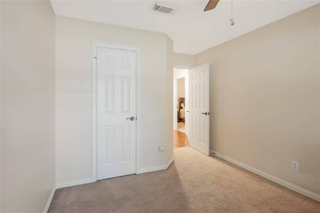 This cozy, neutral-toned bedroom features a ceiling fan, plush carpet. It also includes a closet for added convenience.
