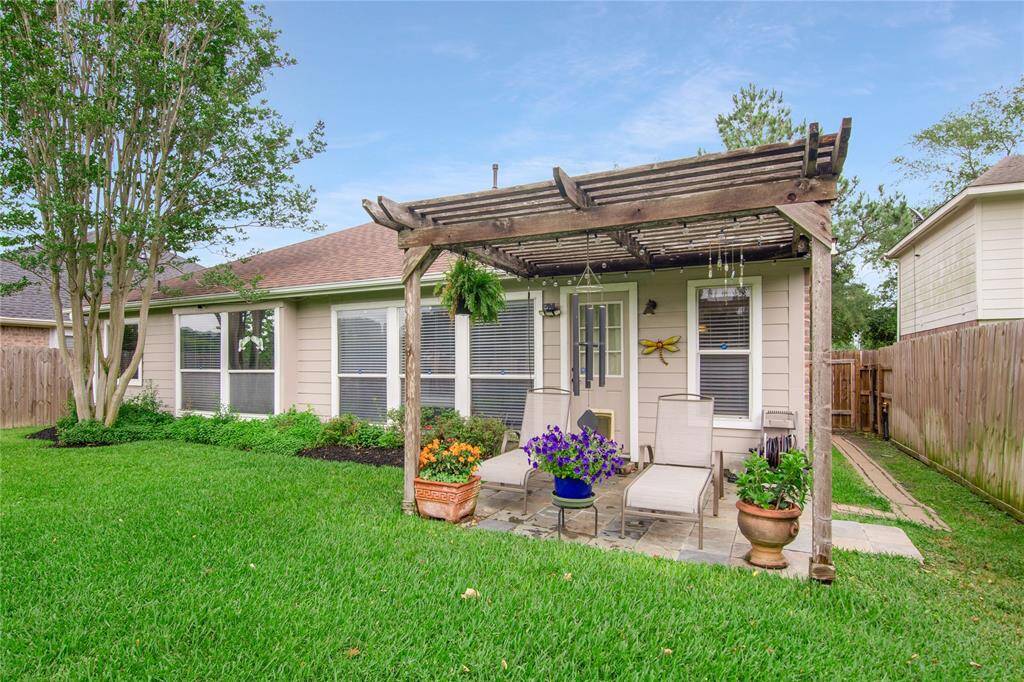 This charming backyard features a well-maintained lawn, a cozy patio, and a wooden pergola, providing an ideal setting for outdoor relaxation.