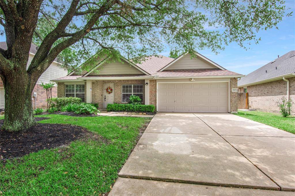 This home features a front porch, two-car garage and a well-maintained front yard. A large tree provides shade, and the landscaping adds curb appeal.