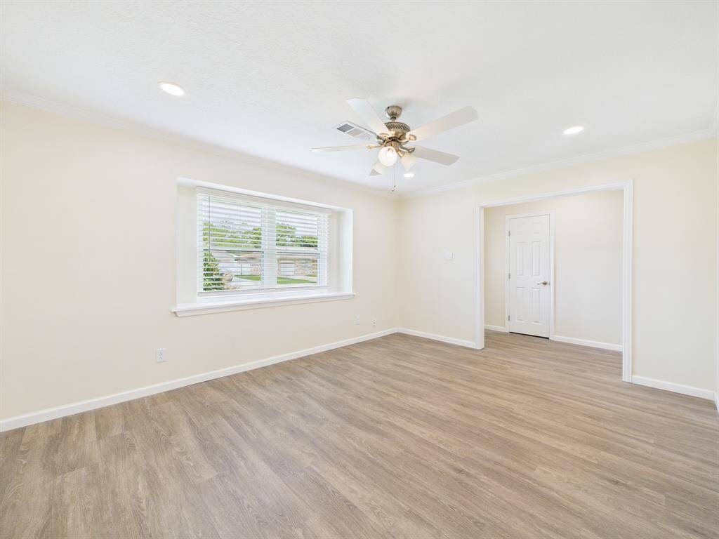 Bright and airy room with light wood flooring, neutral walls, and recessed lighting. Features a ceiling fan, and large window for natural light