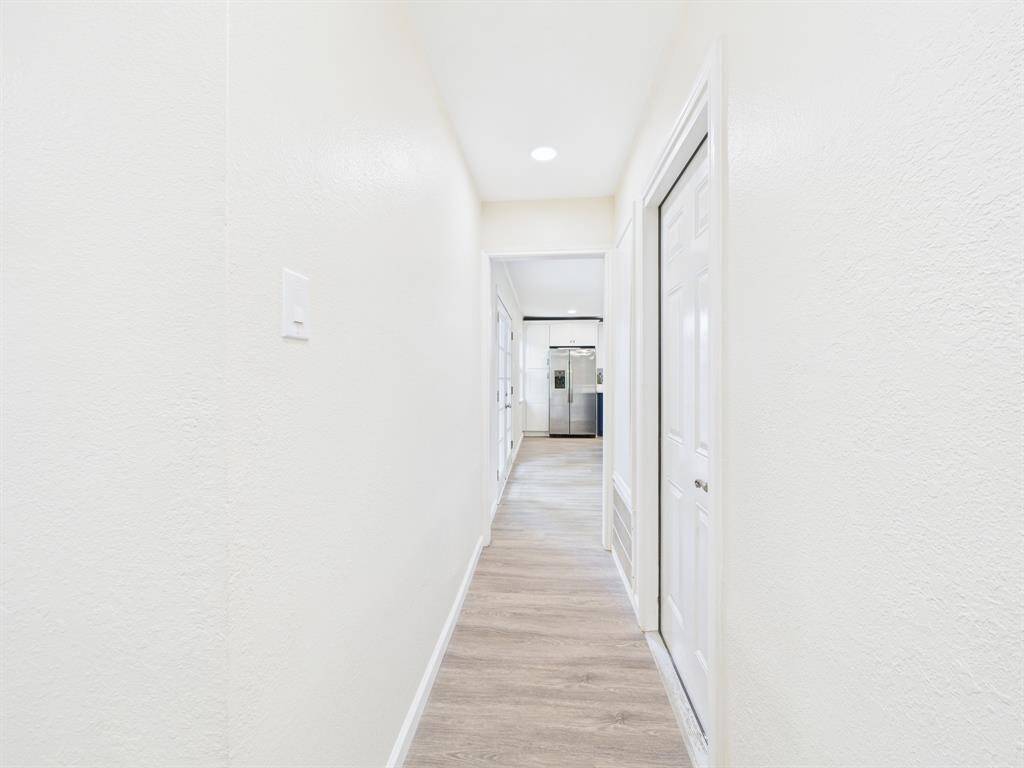 Bright, spacious hallway with light wood flooring and white walls leading to the bedrooms