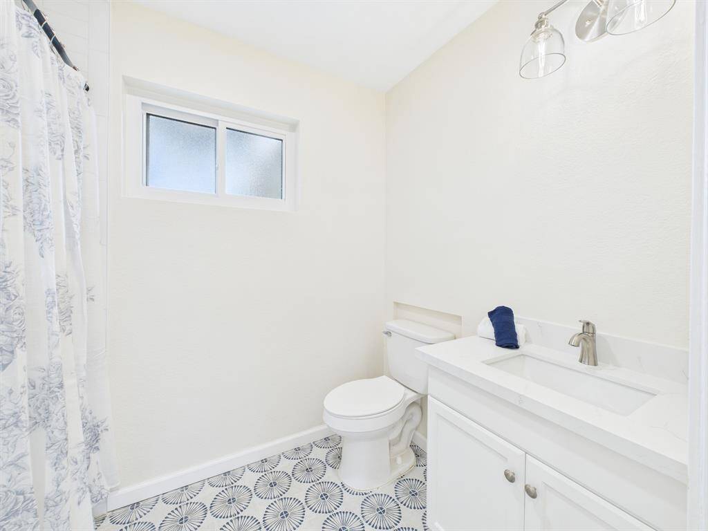 Bright, modern bathroom with an updated vanity & flooring.  It features stylish patterned floor tiles and a frosted window for natural light.