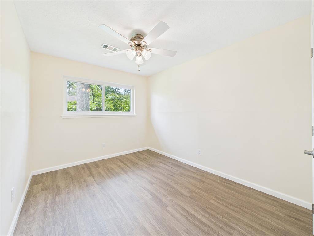 Bedroom #3 features a ceiling fan with lights and a large window offering a view of greenery, creating a fresh and airy atmosphere.