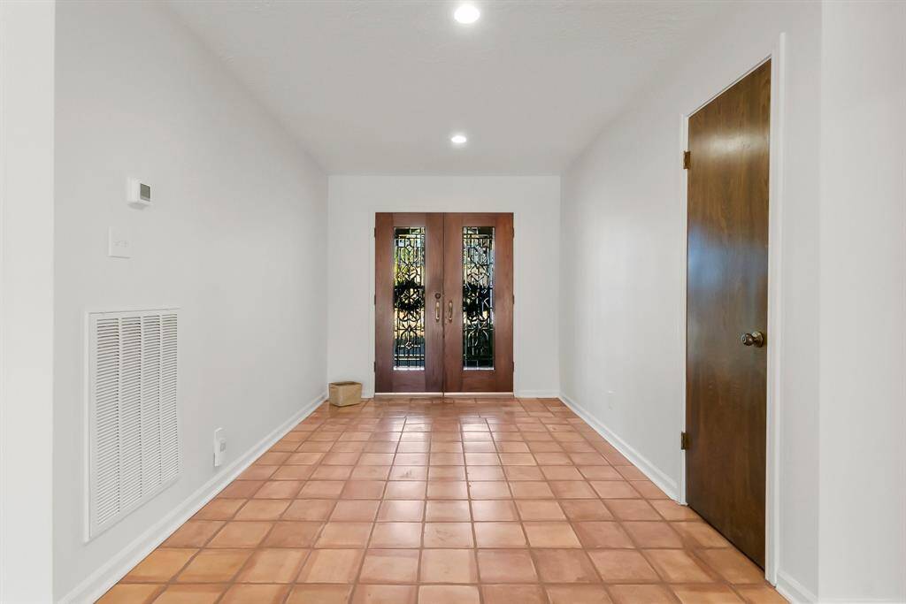 Elegant view of entryway from living room, showcasing stylish glass double doors that welcome natural light.
