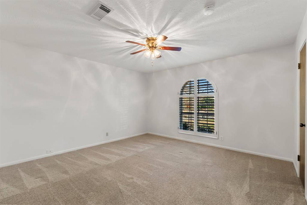 Secondary bedroom with plantation shutters and walk-in closet.