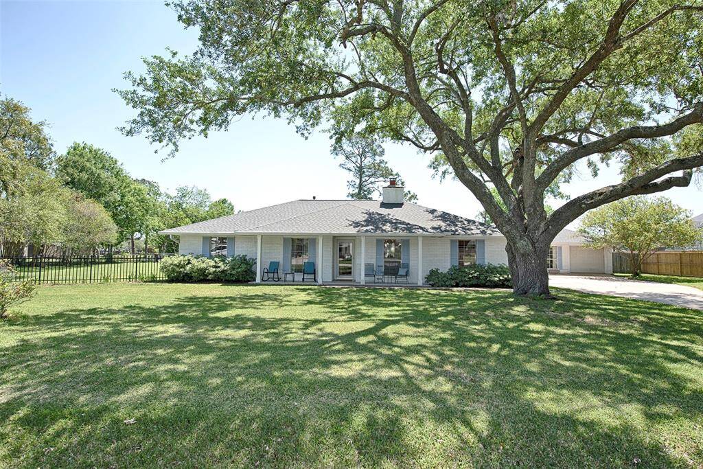 A view of the home showing the gorgeous front porch and fabulous mature Oak trees providing great shade. Certain to help in the summer heat. Roof replaced in 2022!
