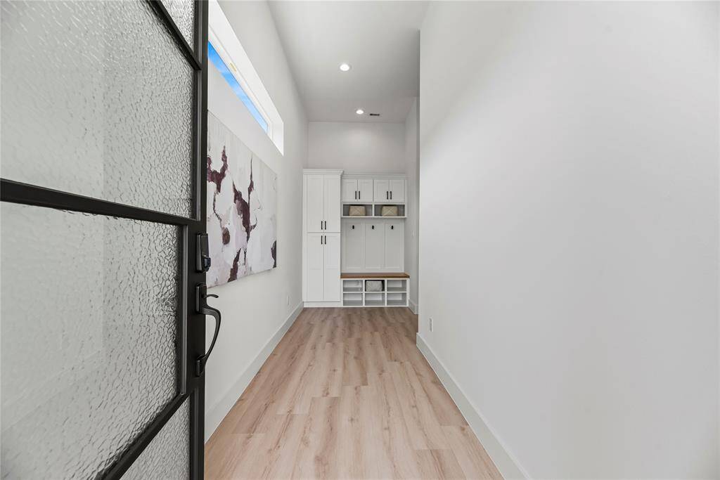 Stunning entry foyer featuring a custom iron door with elegant obscured security glass, 12' ceilings, recessed LED lighting a fixed elongated horizontal windown providing good natural lighting blends sophistication and privacy for your entryway.