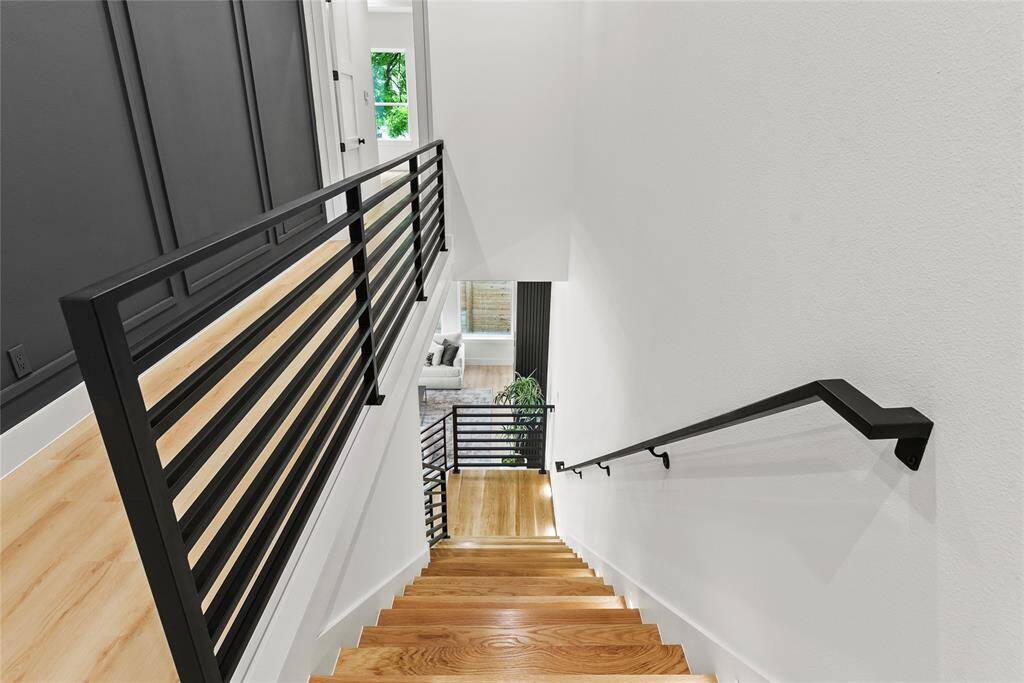 Spacious stairwell with custom designer wrought iron railings with decorative accented walls to greet upstairs.