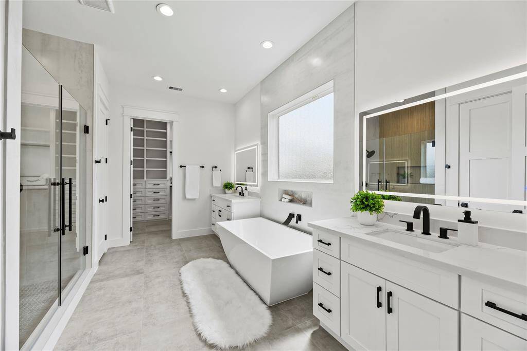 The Primary bath is super large and super luxurious with split vanities each receiving very special mirrors with imbedded LED lighting you will also see you will have an oversized soaker tub  and an oversized shower enclosure with French glass doors, very fancy and original.