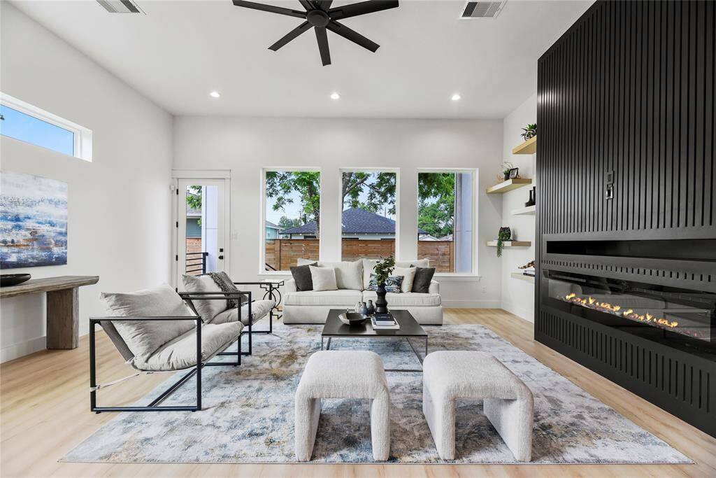 The spacious family room provides warmth and comfort, featuring upgraded floating shelves that blend style with function, a dramatic wall of windows and a horizontal elongated window bathe the entire space in natural light. The upgraded modern oversized ceiling fan adds both flair and good airflow to the area.