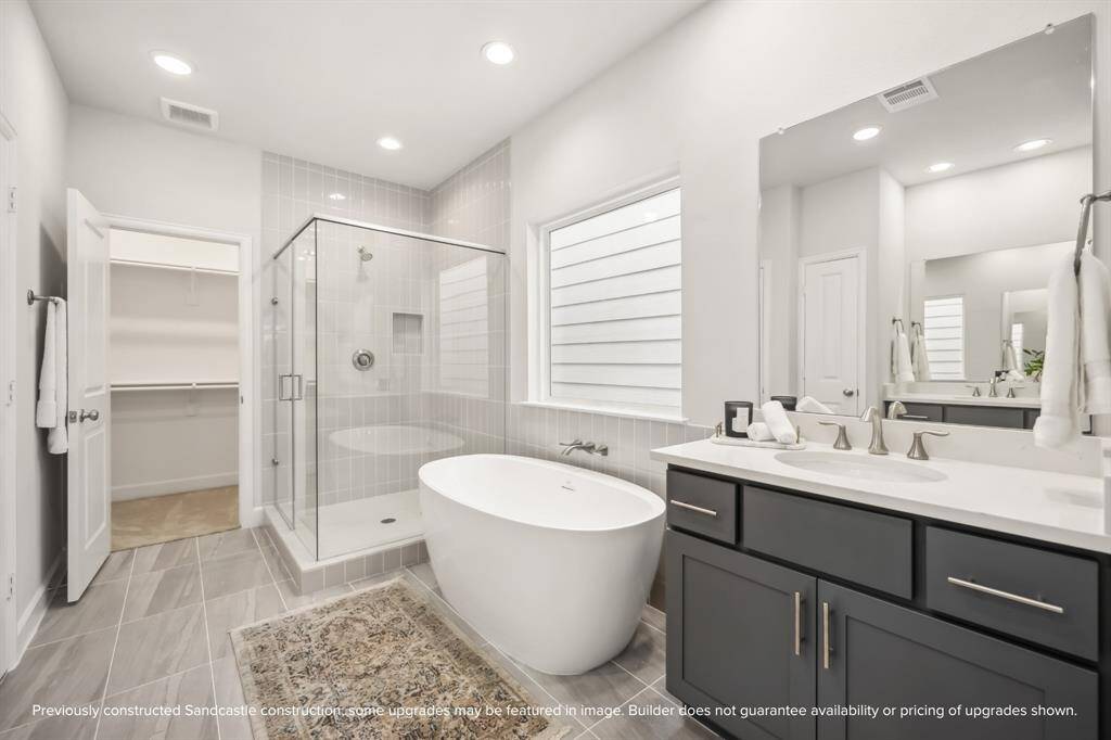 Indulge in a spa-like experience with a freestanding tub, step-in shower, dual sinks, a private water closet, and ample storage.