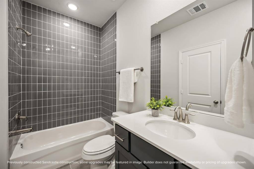 Chic & Functional. An example of a well-appointed secondary bath features stylish dark tile, quartz counters, and Moen fixtures.