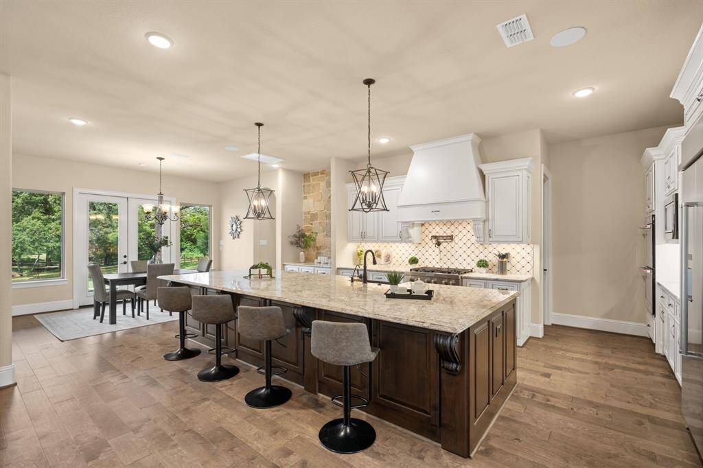 Show off your culinary skills in this stunning chef’s kitchen, where form meets function with high-end stainless steel appliances, a pot filler and an oversized island perfect for prepping, serving, and gathering. Custom soft-close cabinetry, granite countertops, and designer backsplash add timeless elegance, while the open layout keeps you effortlessly connected to the living room, casual dining area, and backyard views.
