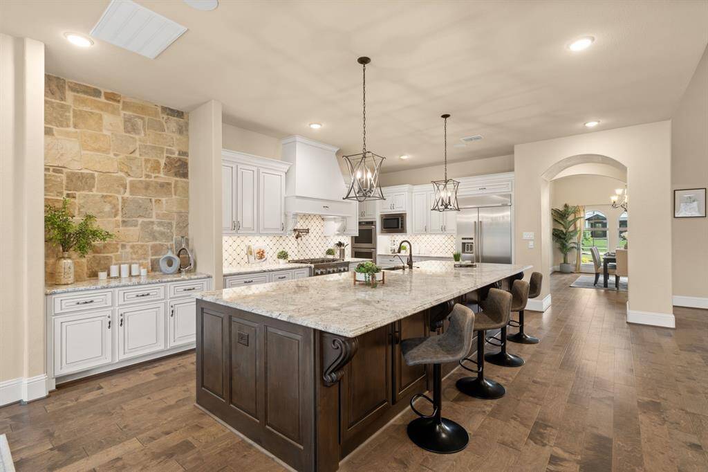 Every detail in this chef’s kitchen reflects thoughtful design and timeless style, from the custom soft-close cabinetry and stone accent wall to the elegant pendant lighting and sleek granite countertops. Designer tile backsplash adds texture and character, while the oversized island delivers the perfect balance of beauty and function in this truly remarkable space.
