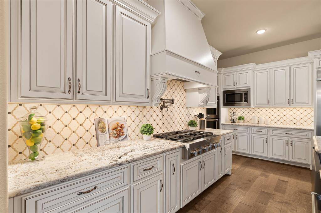 Ditch the takeout and savor home-cooked meals in this beautifully designed kitchen, where the gas cooktop with pot filler and custom hood vent, high-end stainless steel appliances, and custom cabinetry elevate both style and functionality. Whether you're whipping up a quick dinner or hosting guests, this space is crafted to inspire culinary creativity and bring everyone together.