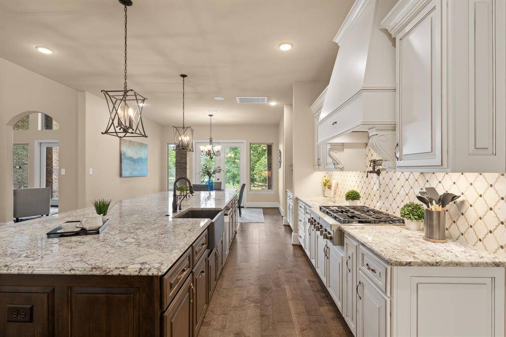 This beautifully designed kitchen seamlessly blends style and functionality, featuring high-end stainless steel appliances, custom cabinetry, sleek granite countertops, and elegant tile backsplash. The open layout flows effortlessly into the casual dining area, where large windows flood the space with natural light, creating a warm and inviting atmosphere for both everyday meals and entertaining.