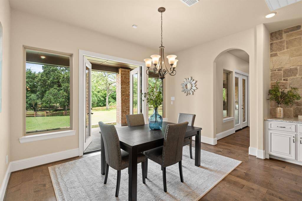 The casual dining area is a light-filled haven, with a stunning chandelier and seamless flow to the outdoors. Open the doors to the covered patio and summer kitchen, creating the perfect spot for dining al fresco or entertaining in style. This space effortlessly blends indoor comfort with outdoor living, making it ideal for both everyday meals and special occasions.