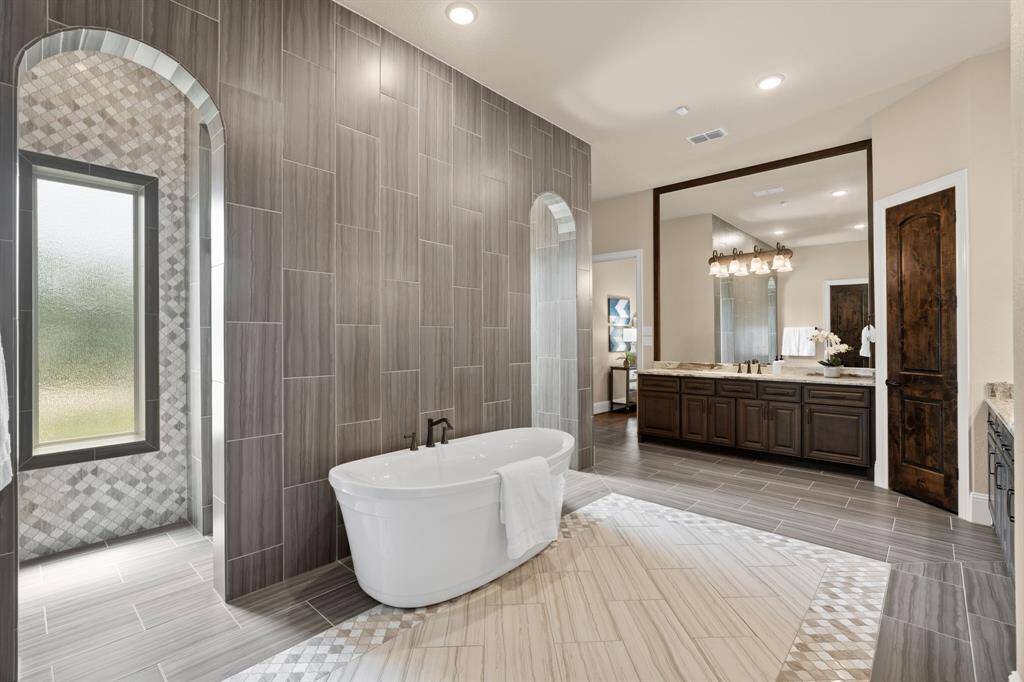 Unwind in the stunning free-standing soaking tub, the perfect retreat for long, luxurious soaks. The bathroom features beautiful tile throughout, with 11' ceilings, soft natural light and elegant arched openings adding to the sense of space.