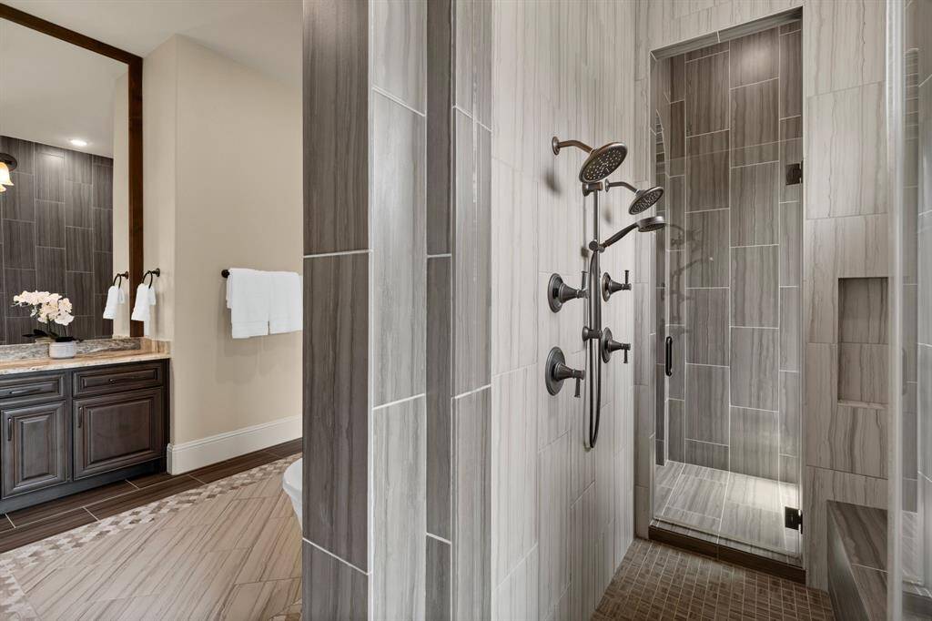 Step into the expansive Greek shower, featuring dual shower heads, body sprays, and a built-in bench for added comfort. Gorgeous tile surrounds the space, while the frameless glass enhances the sleek, modern design, creating a luxurious, spa-like experience right at home.