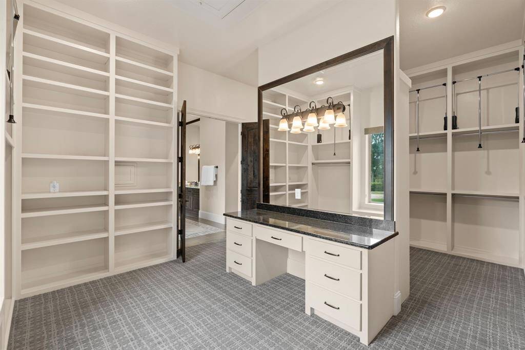 The massive custom walk-in closet is a dream come true, featuring wall-to-wall built-ins, ample shelving, pull-down hanging bars, and a stylish dressing table, and mirrors. With 11' ceilings, this expansive closet offers both exceptional storage and a luxurious, organized space for your wardrobe.
