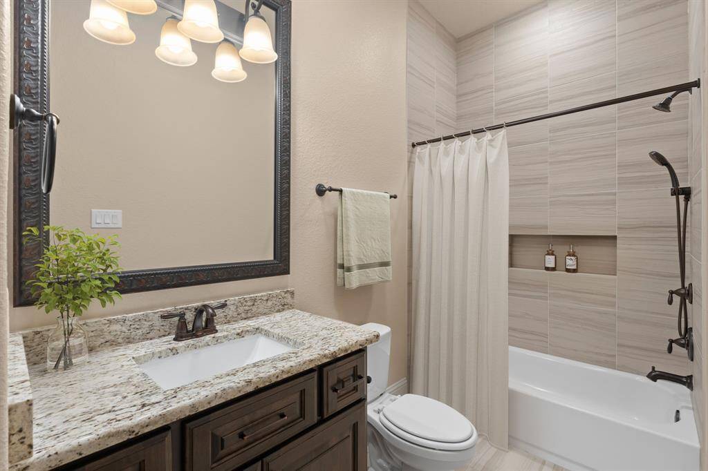 All four bedrooms offer private ensuite bathrooms for added comfort and convenience. This ensuite features a granite-topped single sink vanity with an elegant framed mirror and vanity lights above. It’s complete with a fully tiled tub/shower enclosure with upgraded fixtures, offering both style and functionality.