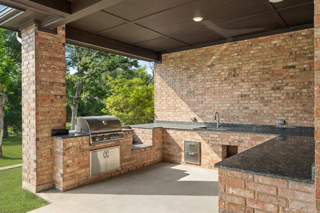 Enjoy outdoor entertaining at its finest with a full covered summer kitchen, featuring stainless steel implements, sleek granite countertops, ample storage, and a convenient sink. This well-appointed space is perfect for grilling, meal prep, and hosting backyard birthday parties or summer cookouts with family and friends.